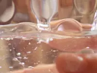 Close-up of arm holding a cup under running faucet