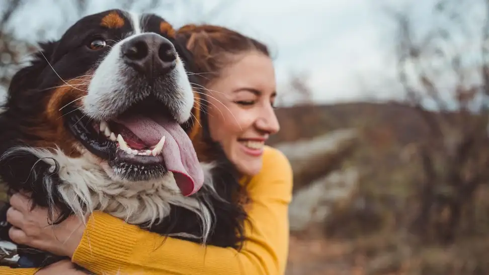 A person hugging a dog outside
