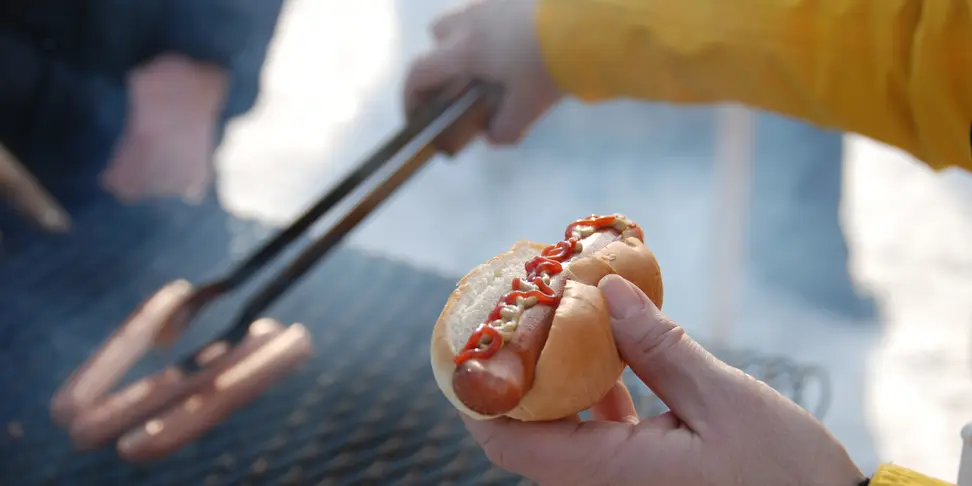 hot dog with ketchup and mustard held over grill