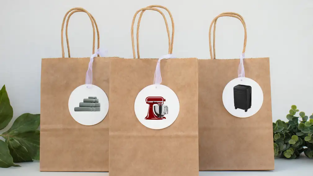Three brown gift bags on a table with gift tags on them