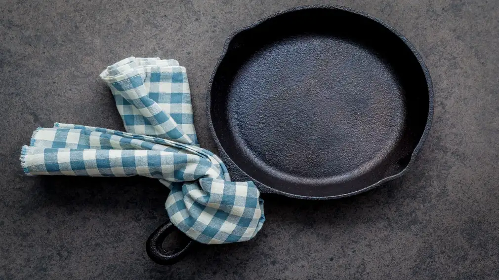 Dirty cast iron with blue and white checkered towel tied to the handle