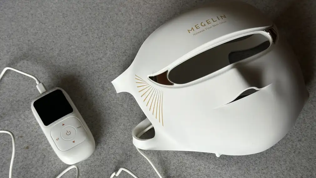 White Megelin LASER & LED mask and remote on grey surface.