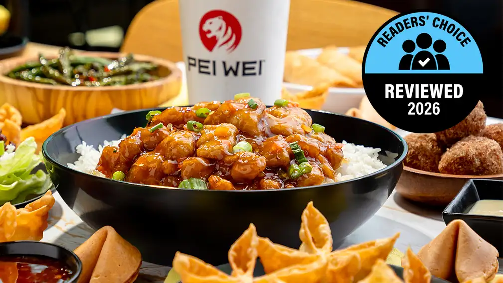 A close-up of a Pei Wei beef lo mein bowl with noodles, green beans, red peppers, and glazed beef on an orange branded background, with a Pei Wei cup visible and a Readers' Choice Reviewed 2026 badge.