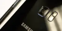 Close-up of a black Samsung smartphone with a built-in camera lens and flash bulb.