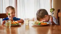 Two boys at a table refusing to eat