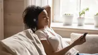Woman sits on her couch meditating