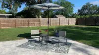 A patio set-up with an outdoor rug, two chairs, small table, and an umbrella.