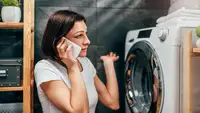 Woman on the phone standing next to washer