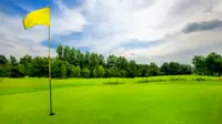 A yellow flag at the 18th hole on a golf course