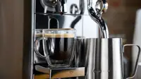 A close-up photo of the Breville Nespresso Creatista brewing an espresso shot and frothing milk.