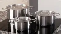 A set of stainless steel pots on an induction cooktop