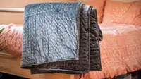 the gravity blanket hangs on the end of a bed