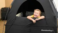 A child peeks out of a black SlumberPod.