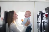 Young mom, playing with her toddler boy on board an airplane while going on a trip.