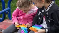 Two girls play with colorful Pop Its