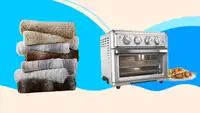 A stack of towels and a stainless steel toaster oven against a blue background.