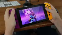 Person holds a Nintendo Switch while playing Fortnite