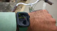 A close-up of the Apple Watch Series 7, in green, showing its cycling workout tracking, with the handlebars of a bicycle in the background.
