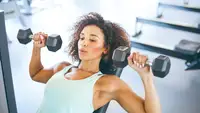 A woman using dumbbells for a chest press at the gym.