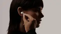 A person puts an AirPod into their ear.