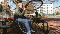 Person outdoors on sports court adjusting wheels for wheelchair.