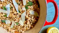 White beans, herbs, and shaved parmesan in a red Dutch oven.