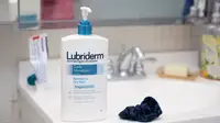 A large bottle of body lotion standing on the side of a sink.