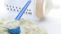 An image of powdered baby formula sitting on a counter near an empty baby bottle.