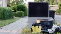 A TV sitting in a trash pile on the curb