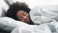 Woman sleeping happily in bed with white covers