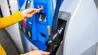A person inserts their bank card into a gas pump.