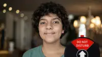 A young boy smiling at the camera. In the corner of the image is an round office privacy sign set to "Do Not Disturb"