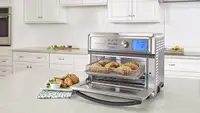 A Cuisinart Toaster Oven is being used on a kitchen table.