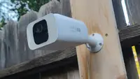 Close up of an outdoor security camera posted to a fence.