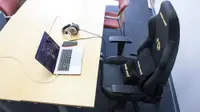 The AndaSeat Phantom 3 gaming chair placed in front of an office desk with a laptop and a pair of headphones.