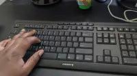 A person's hand touching a black keyboard