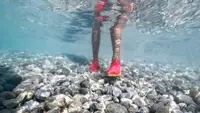 person wearing water shoes shown underwater