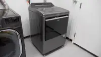 A gray Whirlpool dryer placed in a laundry room.