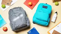 An L.L. Bean backpack and JanSport backpack laying on a table surrounded by school supplies and apples.