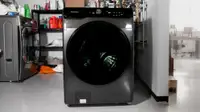 A black washing machine with a front-load door sits in a storage room