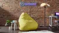 Yellow Floyd Squishy Chair in front of brick wall next to side table, and floor Y-Lamp.