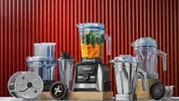 Several Vitamix blenders and accessories in front of a red backdrop