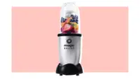 Magic Bullet blender filled with fruit on a pink background