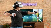 A person wearing a white PSVR 2 headset mimicking pulling back a bow and arrow in front of a TV