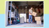 Person standing in garage while holding moving boxes indoors.