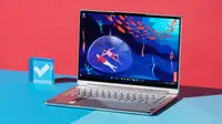 A silver laptop open and powered on against a blue and red backdrop.