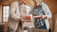 Senior couple organizing books into box at home.