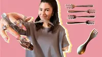 One-armed person smiling while holding up assorted cutlery perfect for one-handed use that makes eating easier.