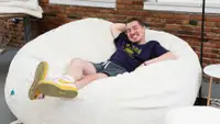 A man smiling while he's laying on the bean bag.