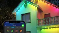 A house lit up by Govee lights and a phone displaying the Govee app.